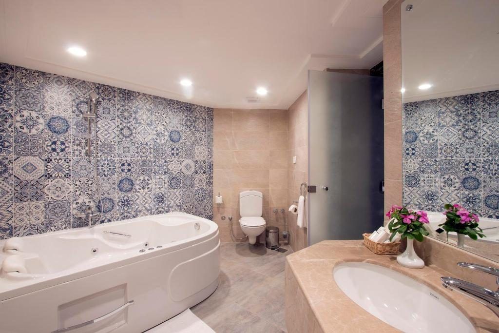 Bathroom with patterned blue tile walls, jacuzzi tub and marble vanity