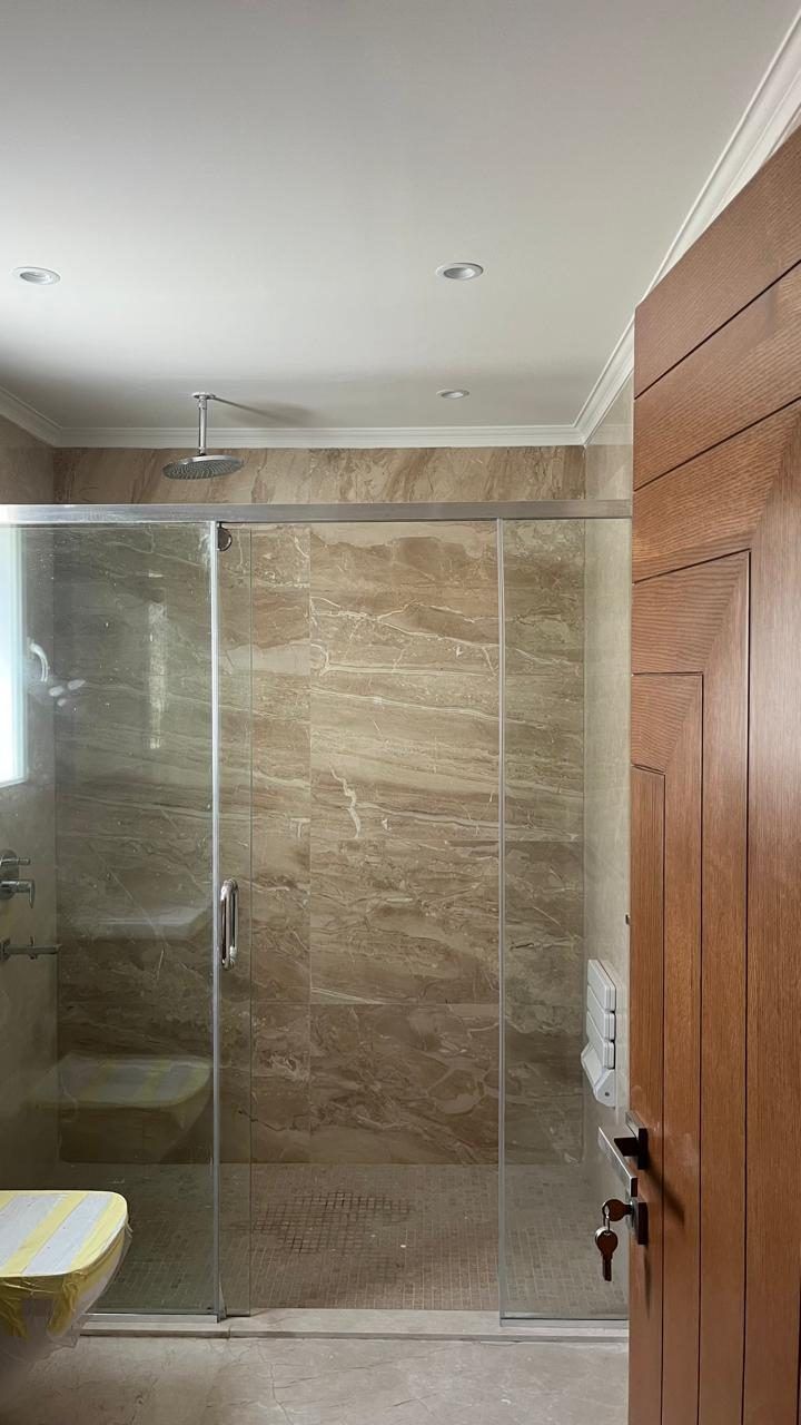 Bathroom with walk-in glass shower and travertine-look tiles