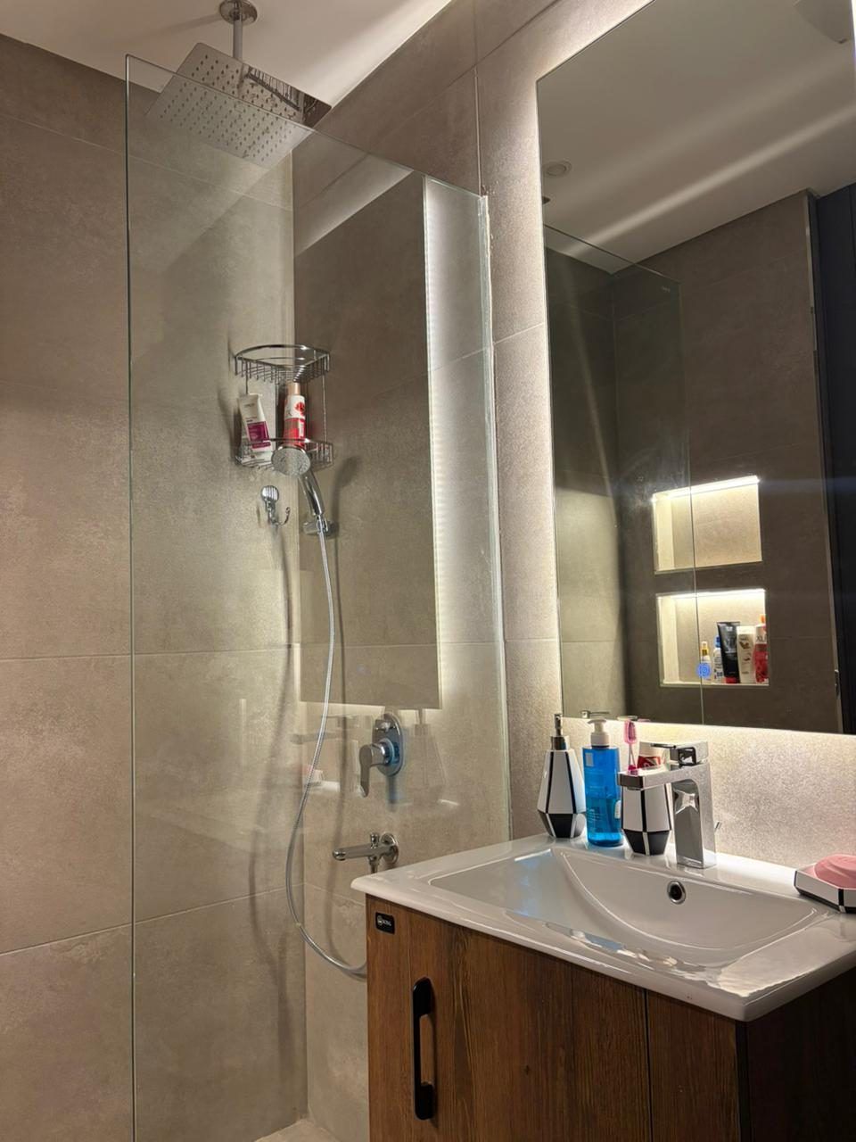 Bathroom with walk-in glass shower, large-format stone tiles and backlit niche