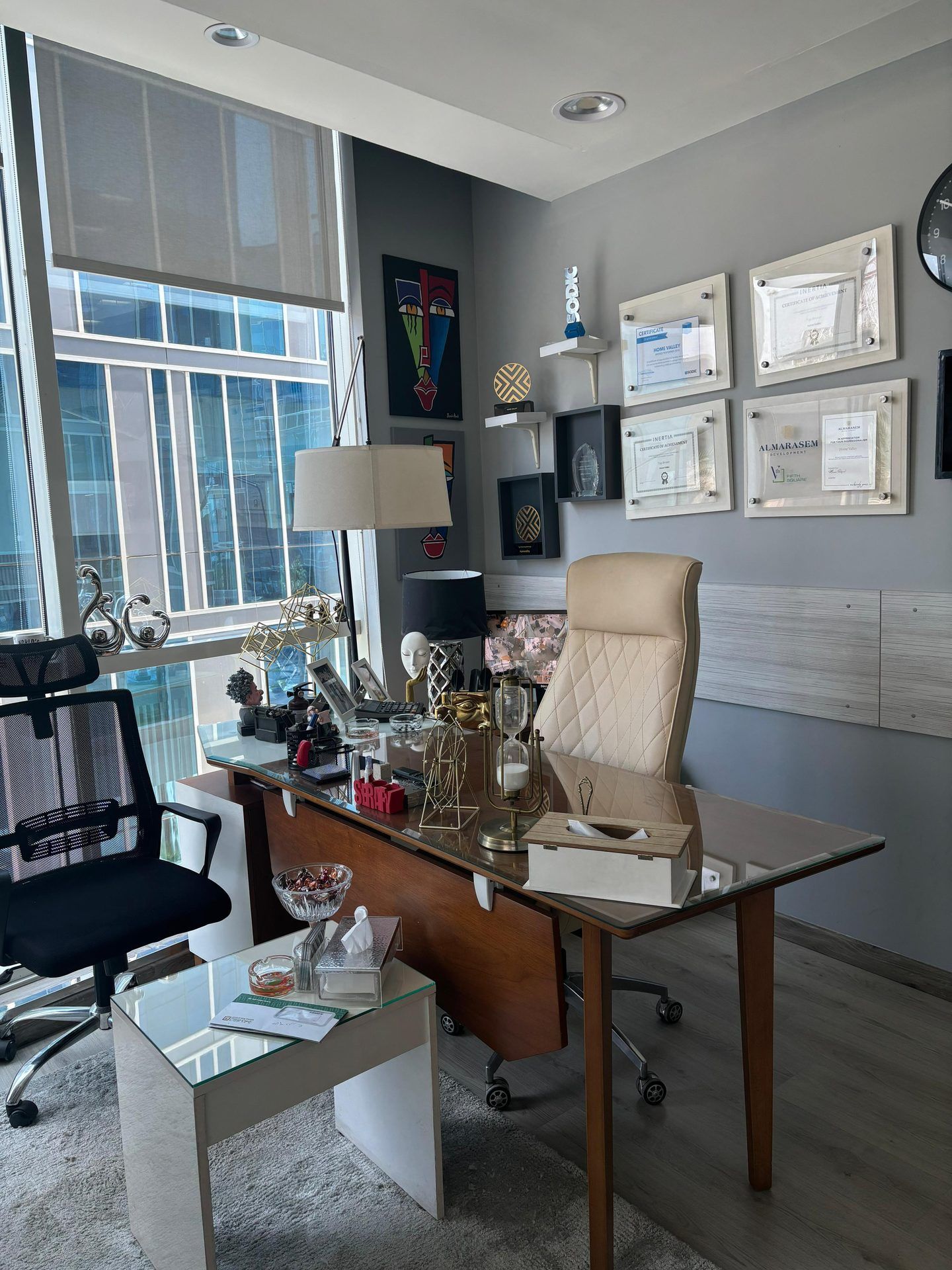 Executive office with floor-to-ceiling windows, walnut and glass desk and cream leather chair