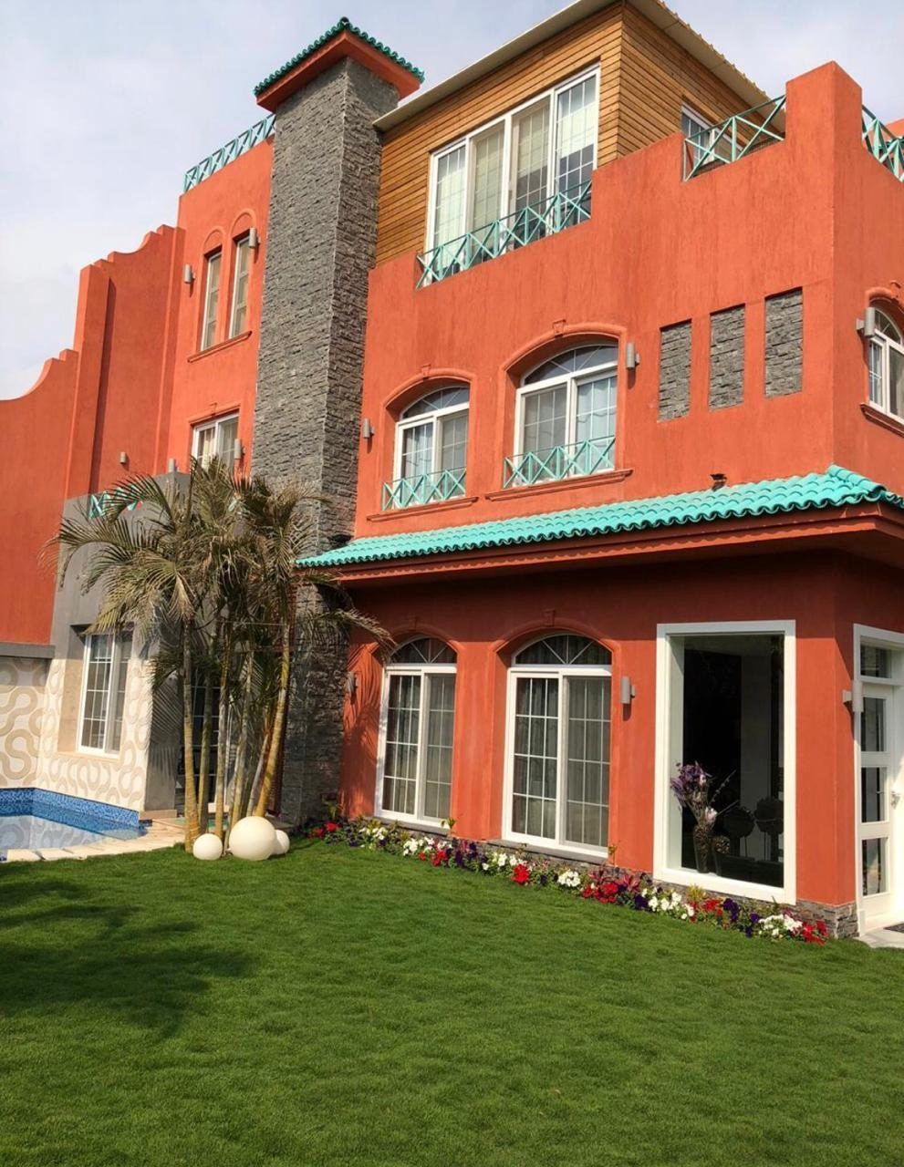 Terracotta town house with turquoise roof trim, arched windows and lawn