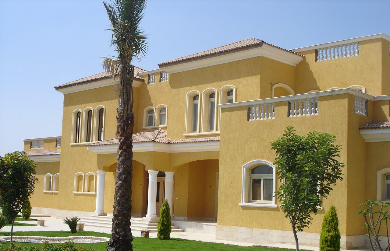 Front facade with columned entrance, palms and planted borders