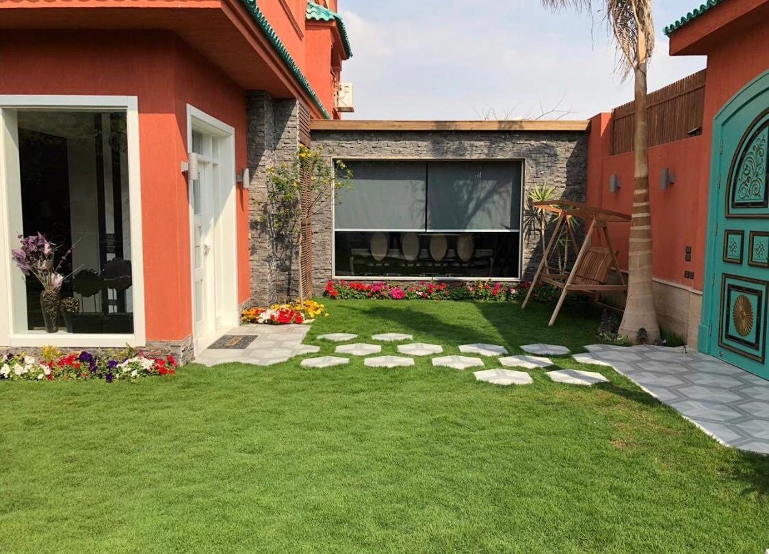 Garden with stepping-stone path, outdoor lounge and carved turquoise door
