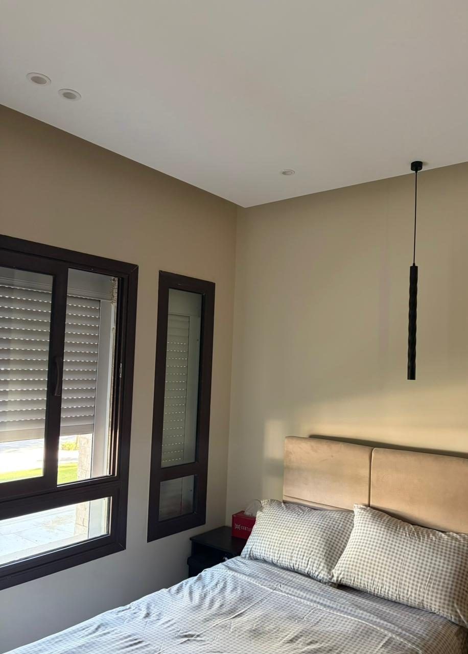 Bedroom with dark aluminium windows, upholstered headboard and pendant light