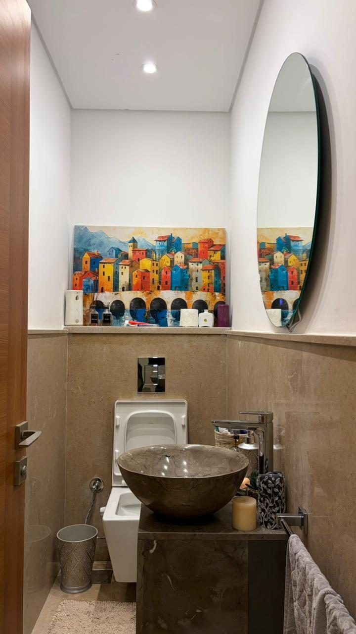 Guest WC with travertine wainscot, stone vessel basin and round mirror