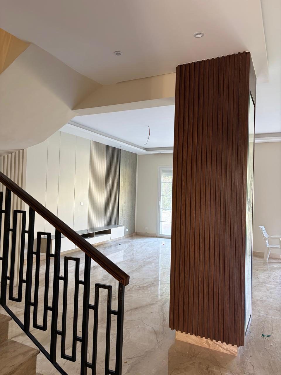 Living area with walnut slat column, marble floor and geometric balustrade