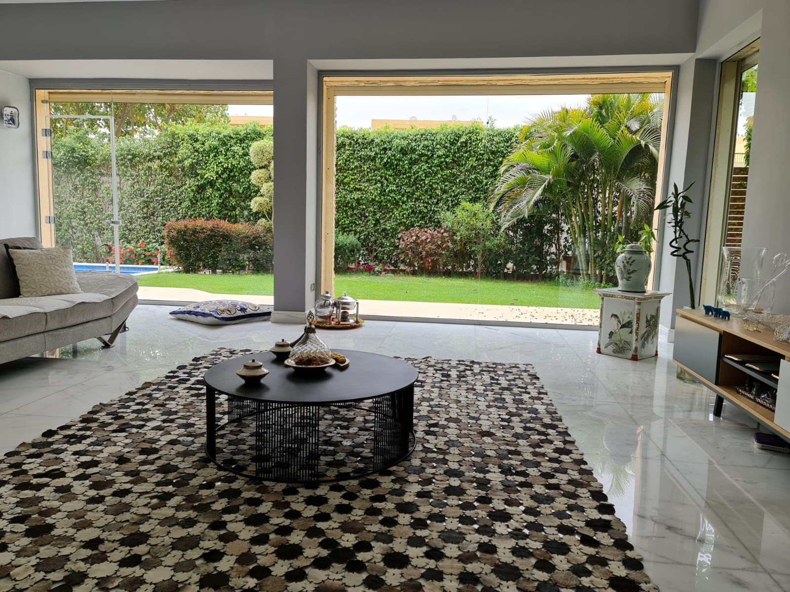 Living room with white marble floor and full-height glazing onto the garden