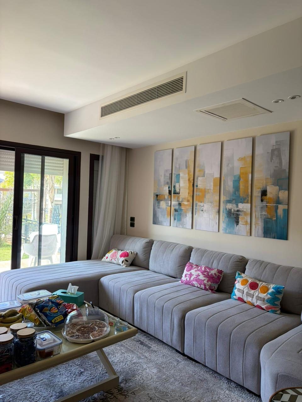 Living room with grey sectional and full-height windows onto the garden