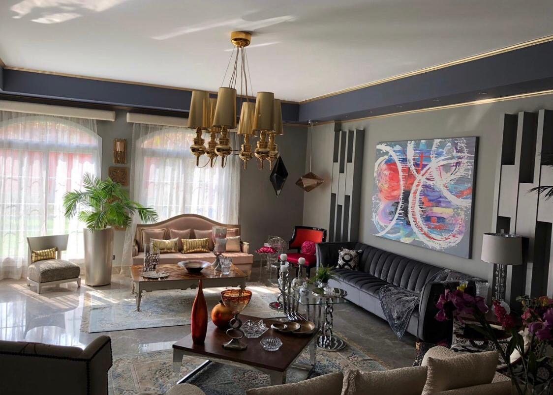 Formal living room with brass chandelier, marble floor and large abstract canvas