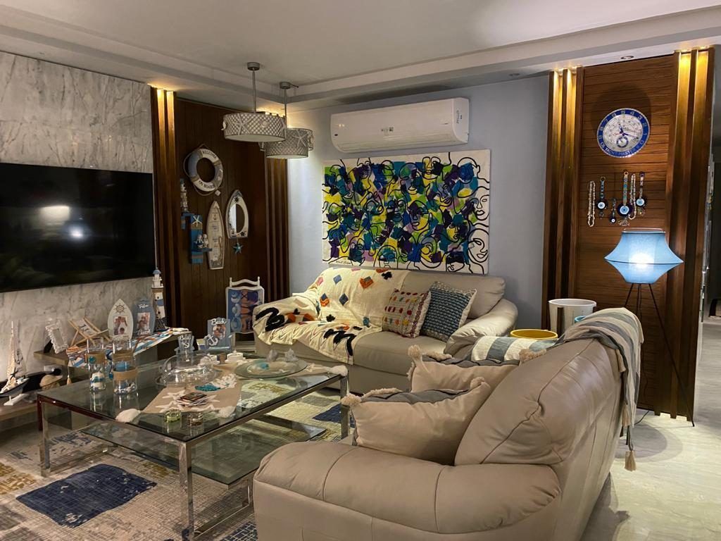 Living room with timber slat partition, marble feature wall, nautical decor and cream leather sofas
