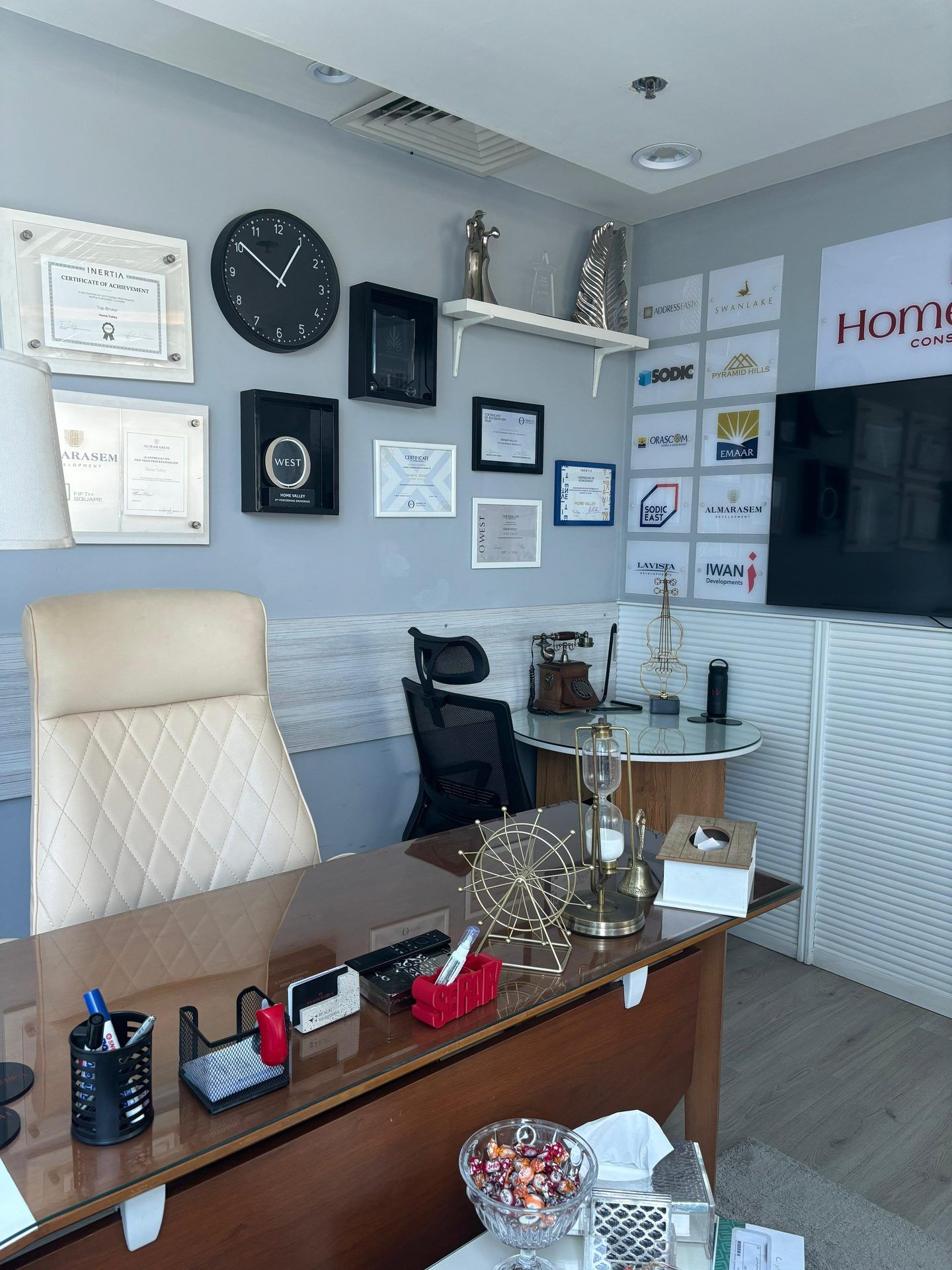 Manager's desk with framed certificates, clock and branded wall display