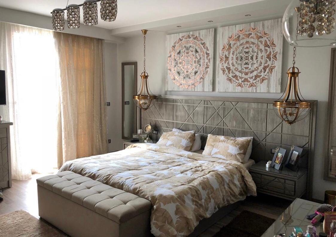 Master bedroom with upholstered headboard, mandala art and brass pendants