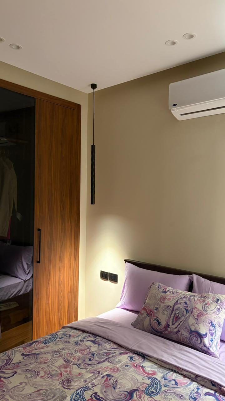 Bedroom with walnut sliding wardrobe, pendant bedside light and soft lilac bedding