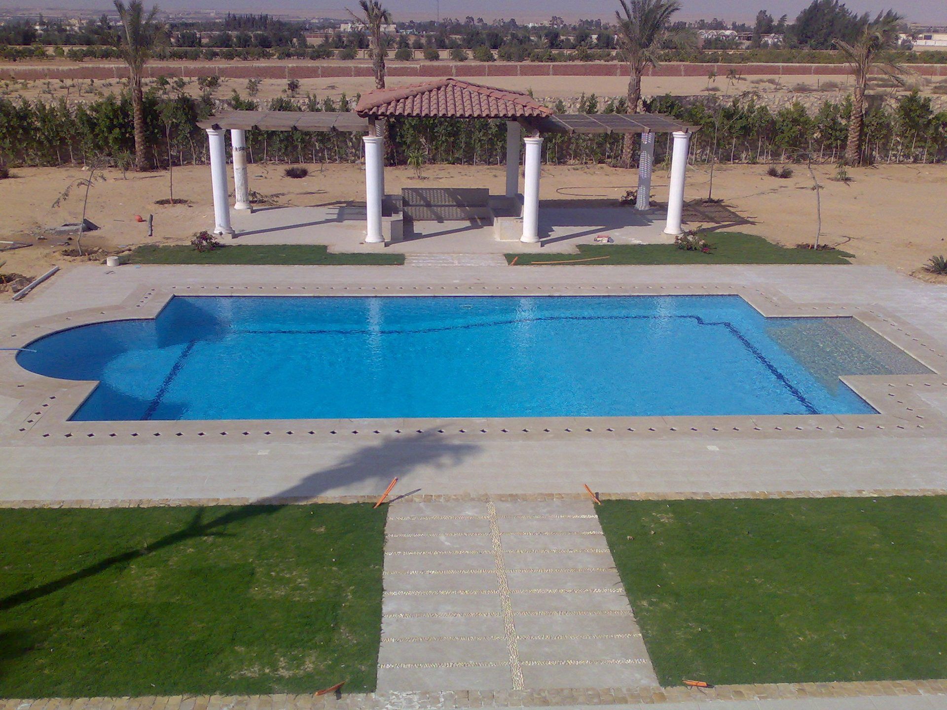 Pool with stone deck and columned pergolas