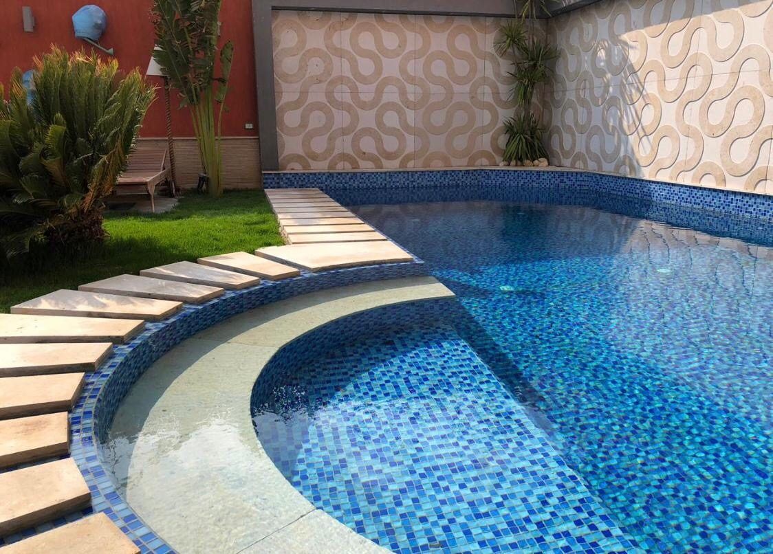 Curved pool steps with blue mosaic and patterned feature wall