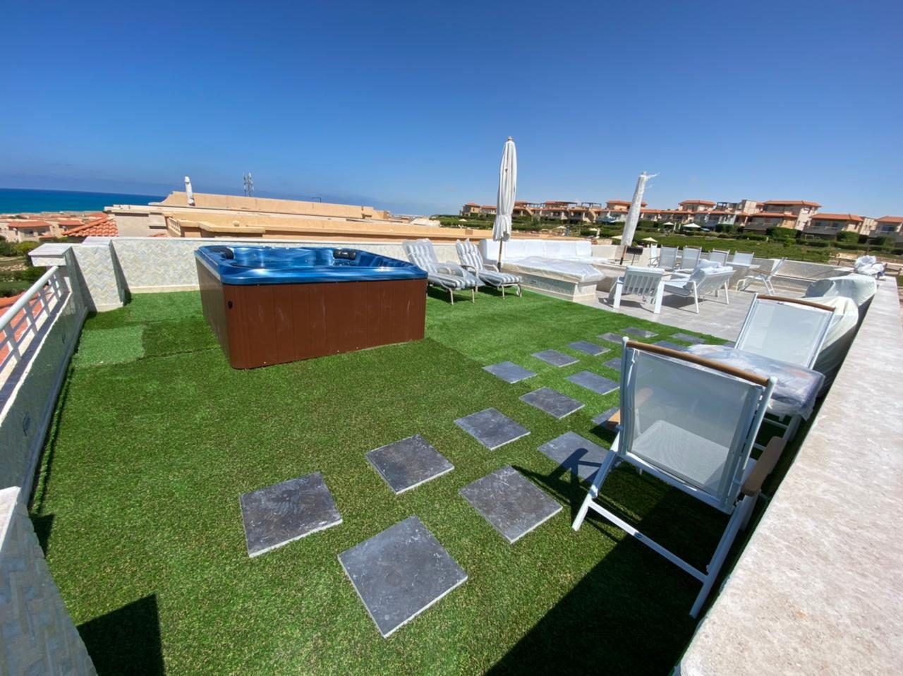 Rooftop hot tub and loungers on artificial grass with a view of the sea