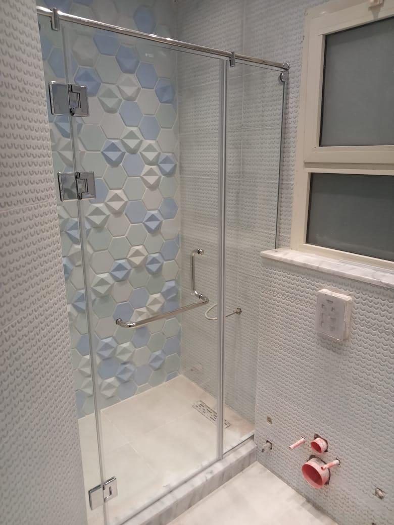 Frameless glass shower enclosure with blue and white hexagon tile wall