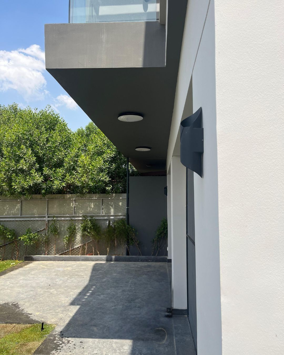 Side garden with paving, wall light and cantilevered balcony