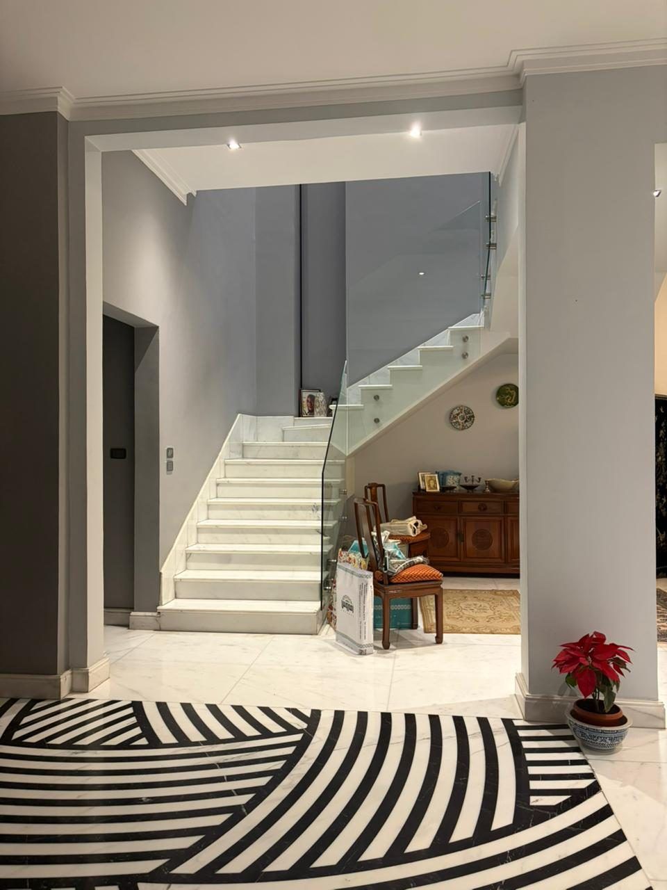 Glass-balustrade staircase above a black-and-white patterned marble floor inlay