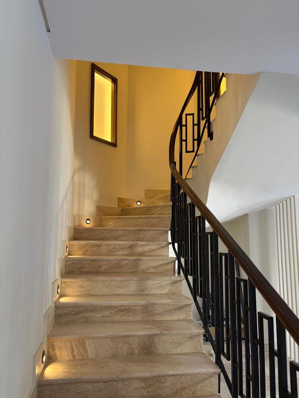 Marble staircase with step lights and geometric metal balustrade