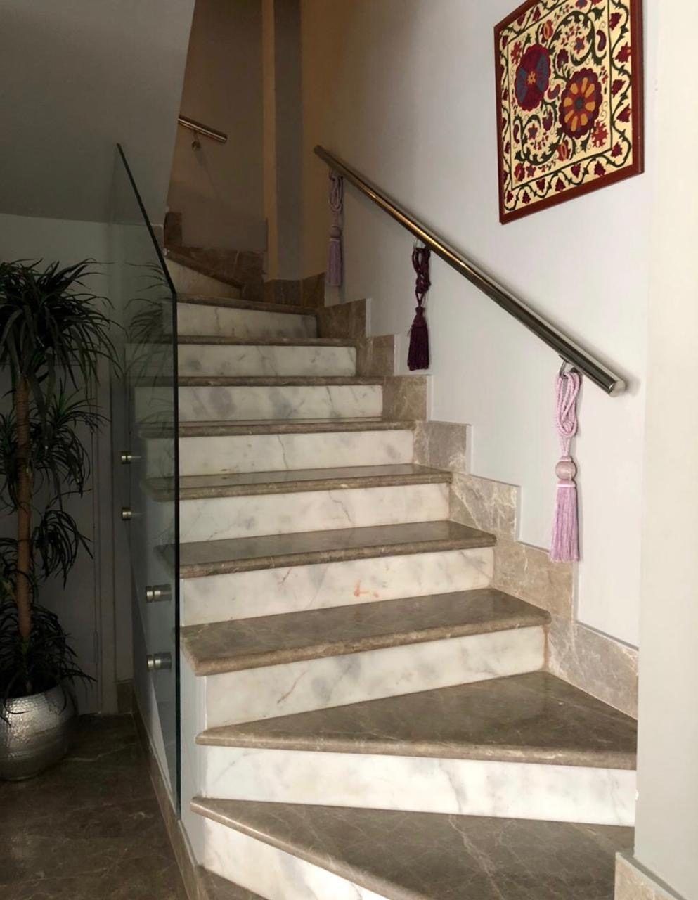 Marble staircase with glass balustrade and embroidered wall hanging