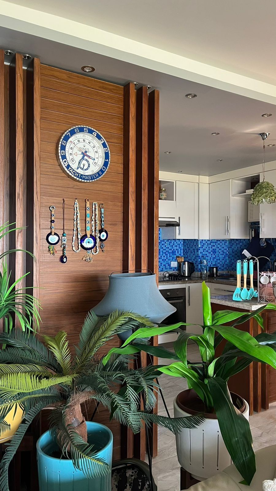 Walnut slat partition with clock and evil-eye decor separating the living area from the kitchen