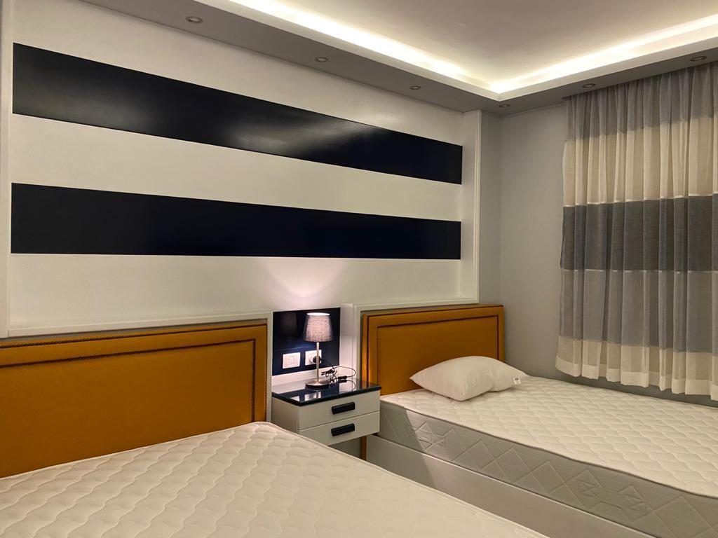 Twin bedroom with navy and white striped feature wall and cove lighting